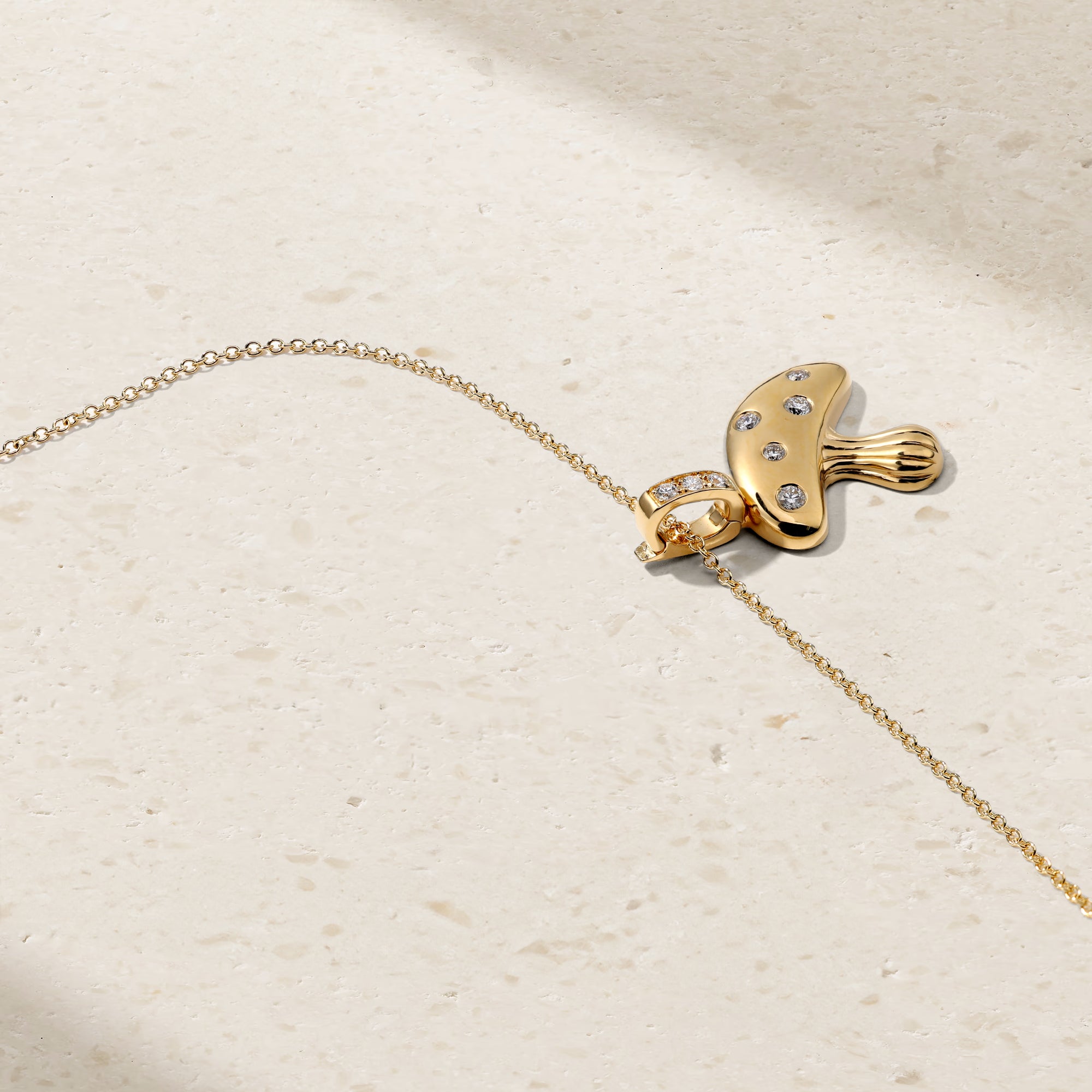 Gold necklace with a unique pendant on a beige background