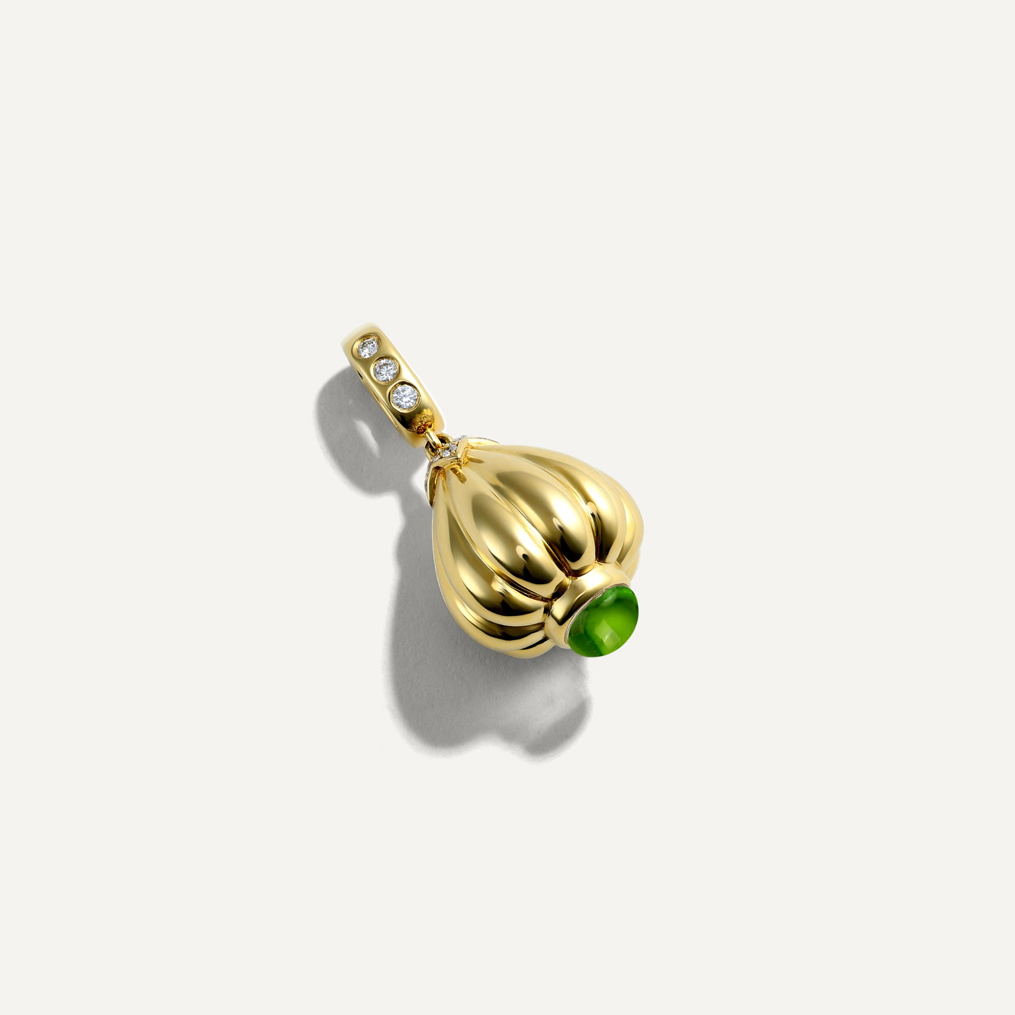 Gold pendant with a green gemstone on a white background
