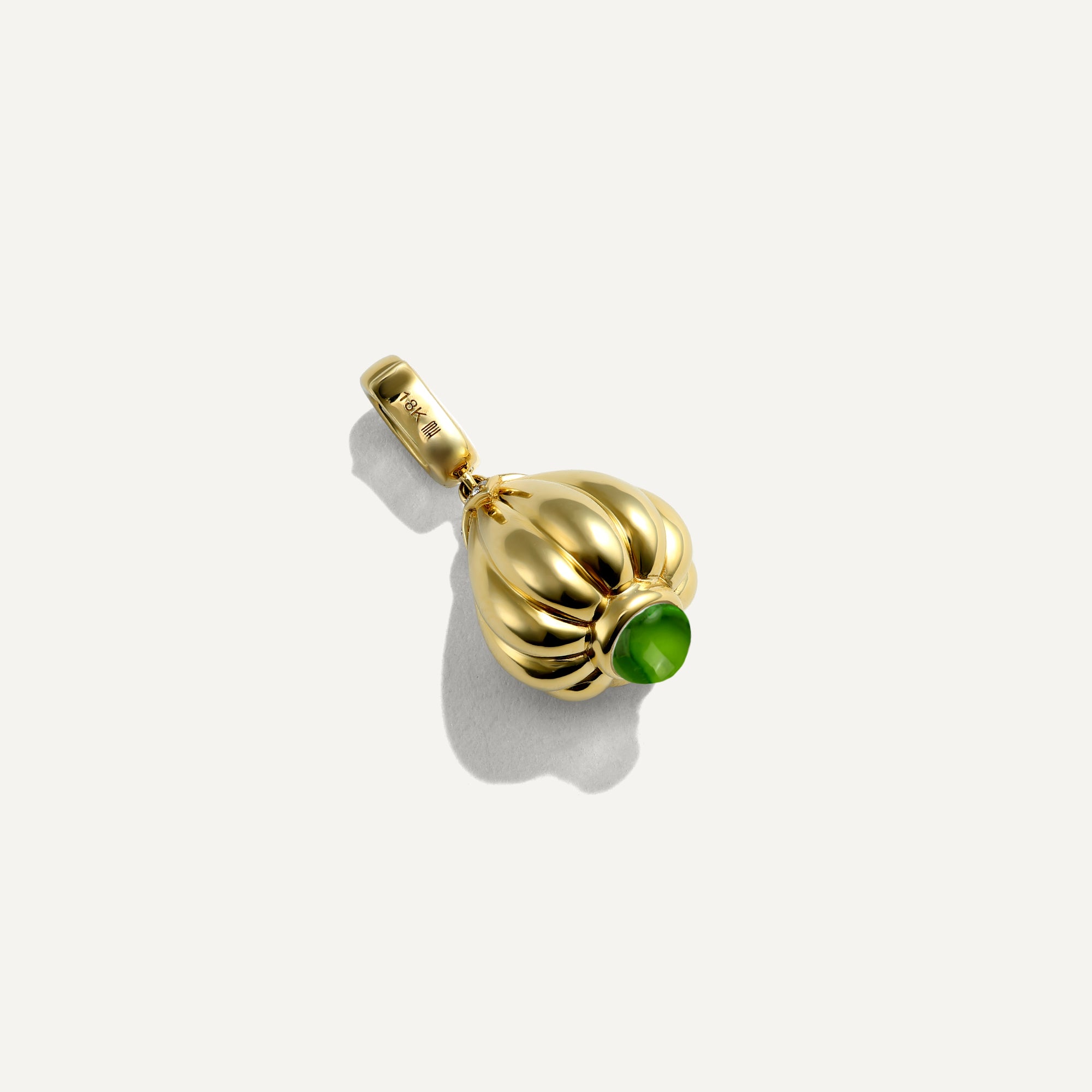 Gold pendant with a green gemstone on a white background