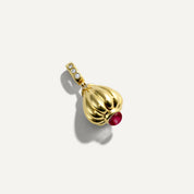 Gold pendant with a red gemstone on a white background
