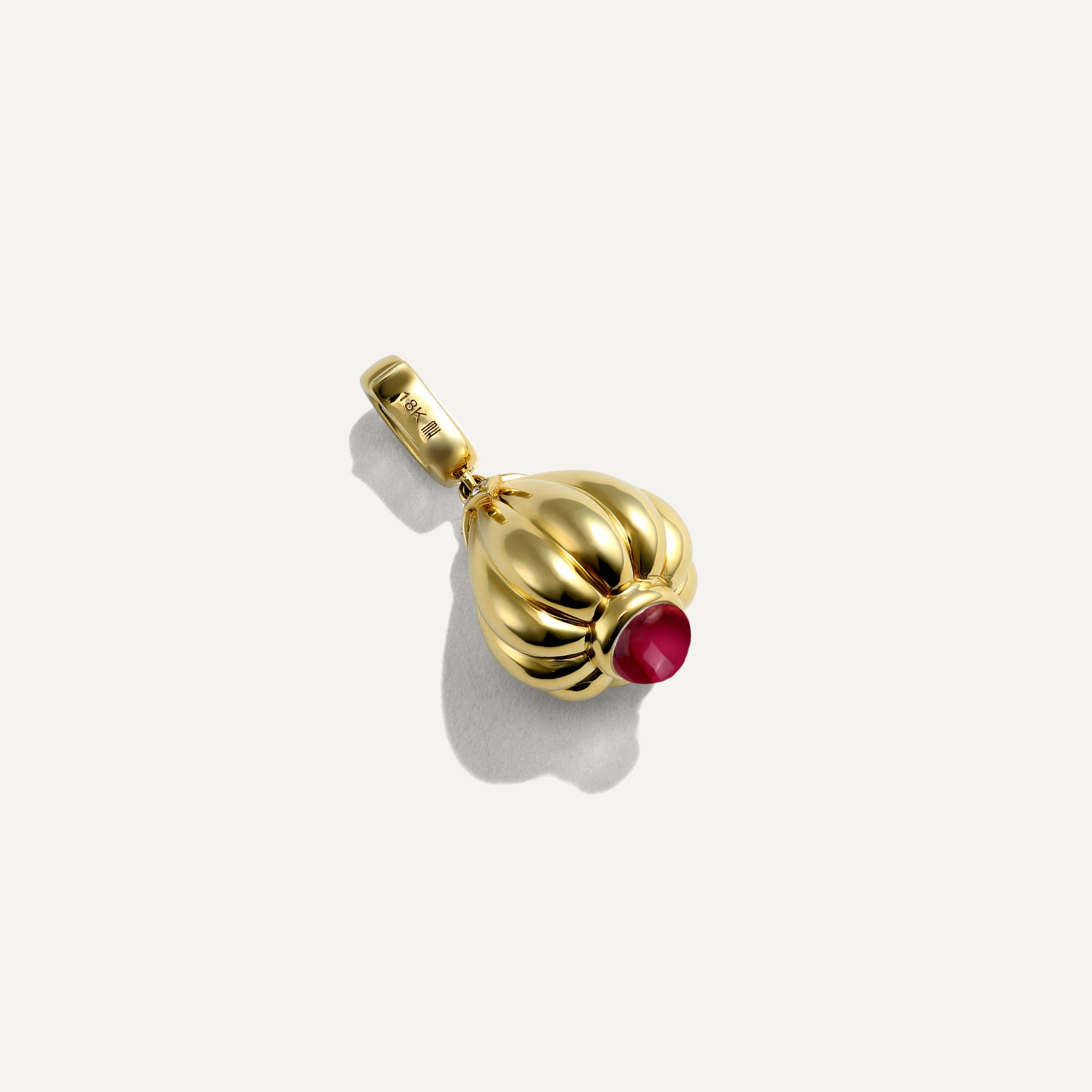 Gold pendant with a red gemstone on a white background