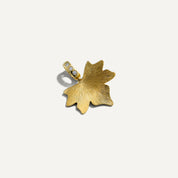 Gold leaf-shaped pendant with embedded stones on a white background