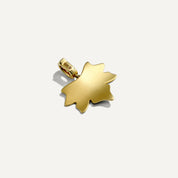 Gold pendant shaped like a leaf on a white background