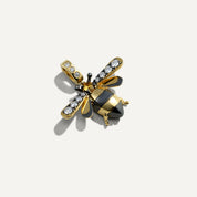 Gold and black bee-shaped pendant with gemstones on a white background