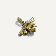 Gold bee-shaped pendant with embedded stones on a white background