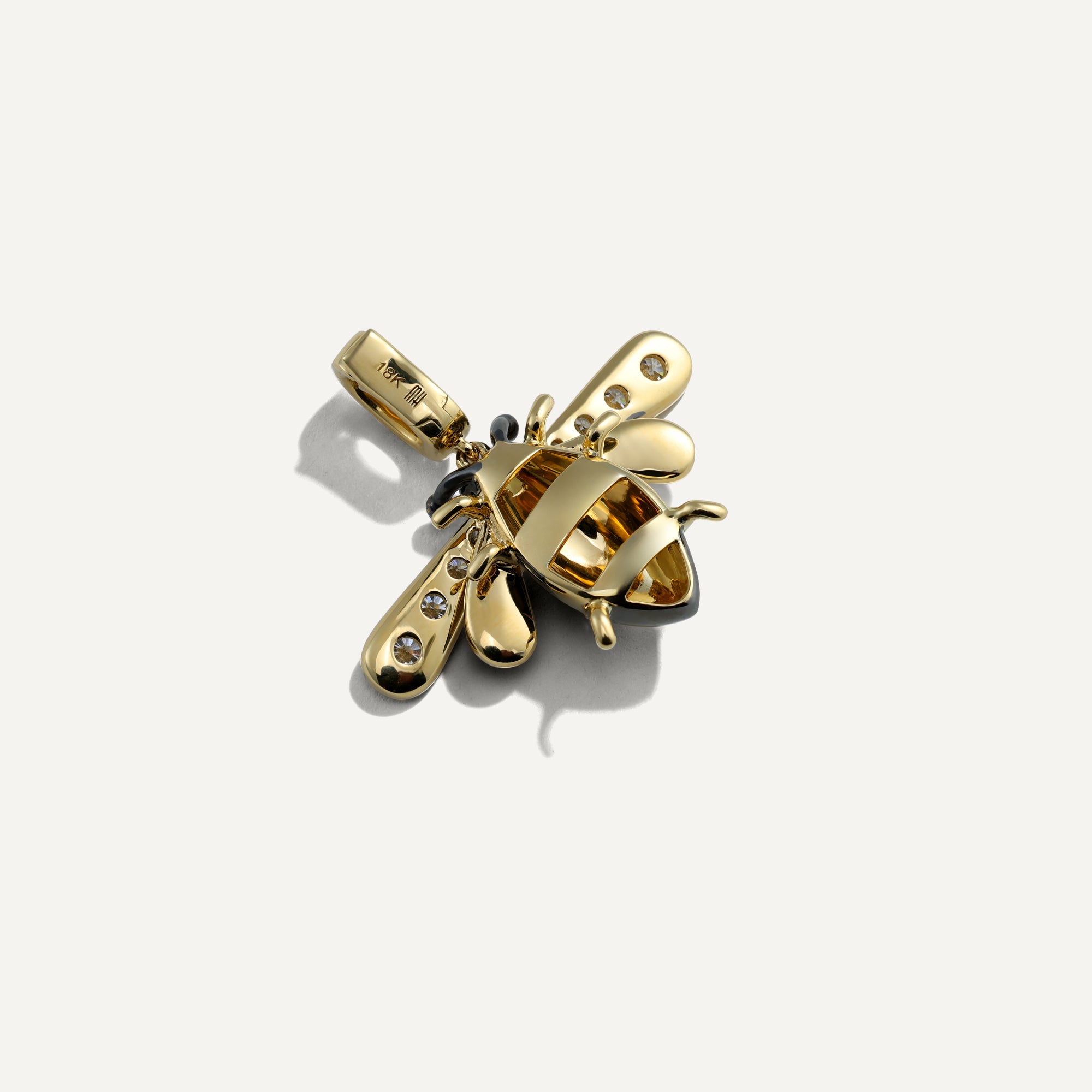 Gold bee-shaped pendant with embedded stones on a white background