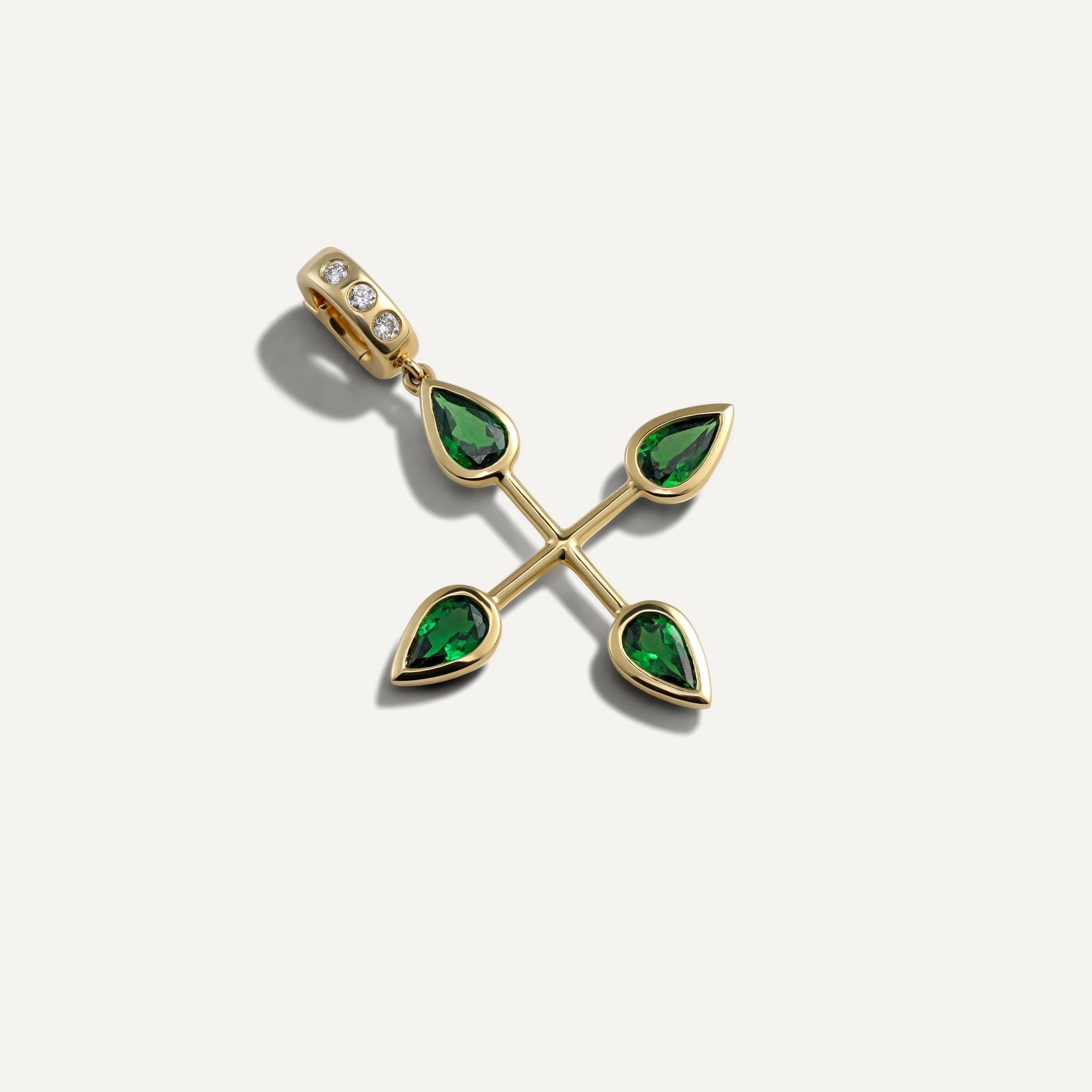 Gold pendant with green gemstones on a light gray background