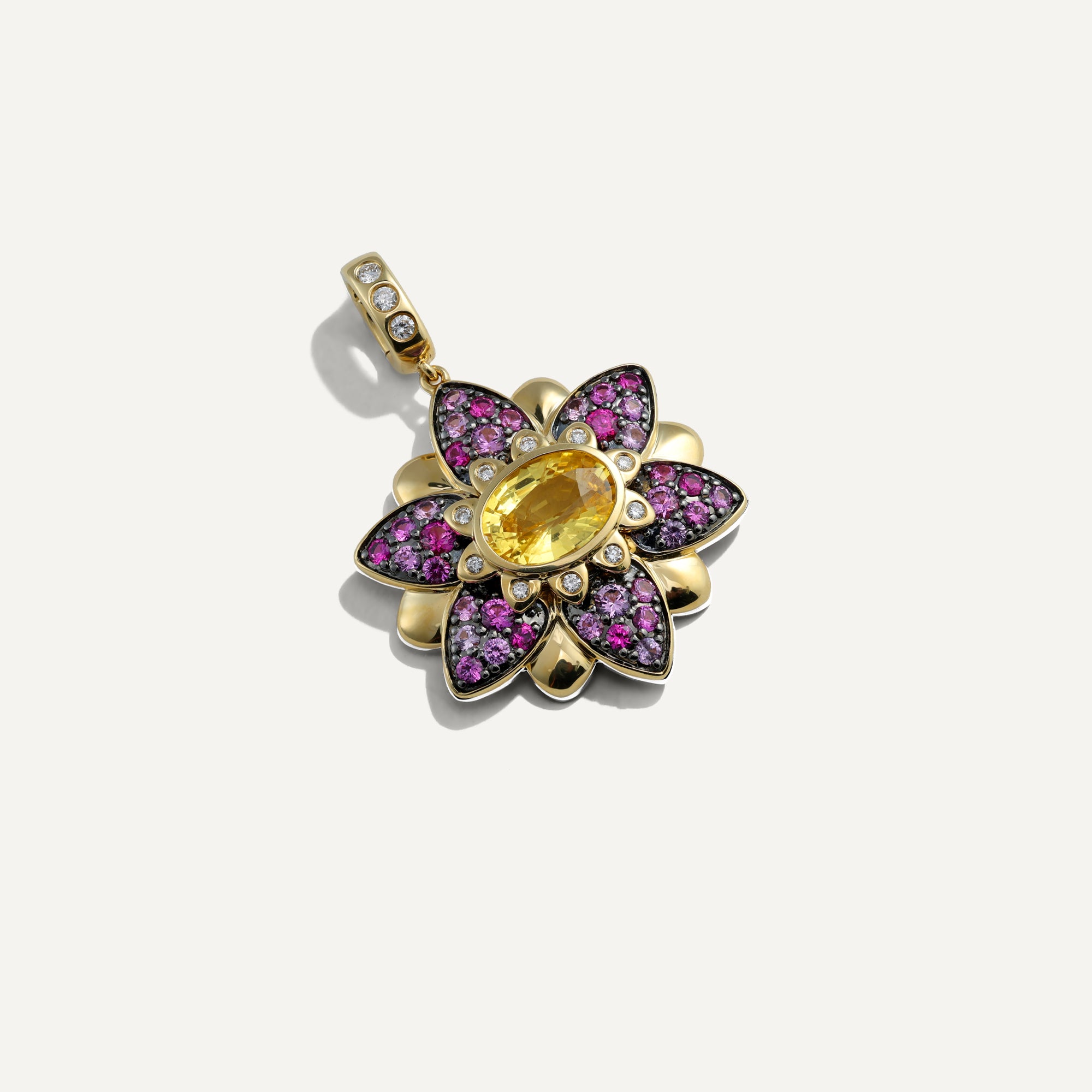 Gold pendant with pink gemstones on a white background