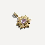 Gold pendant with a pink gemstone on a white background