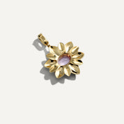 Gold pendant with a central purple stone on a light gray background