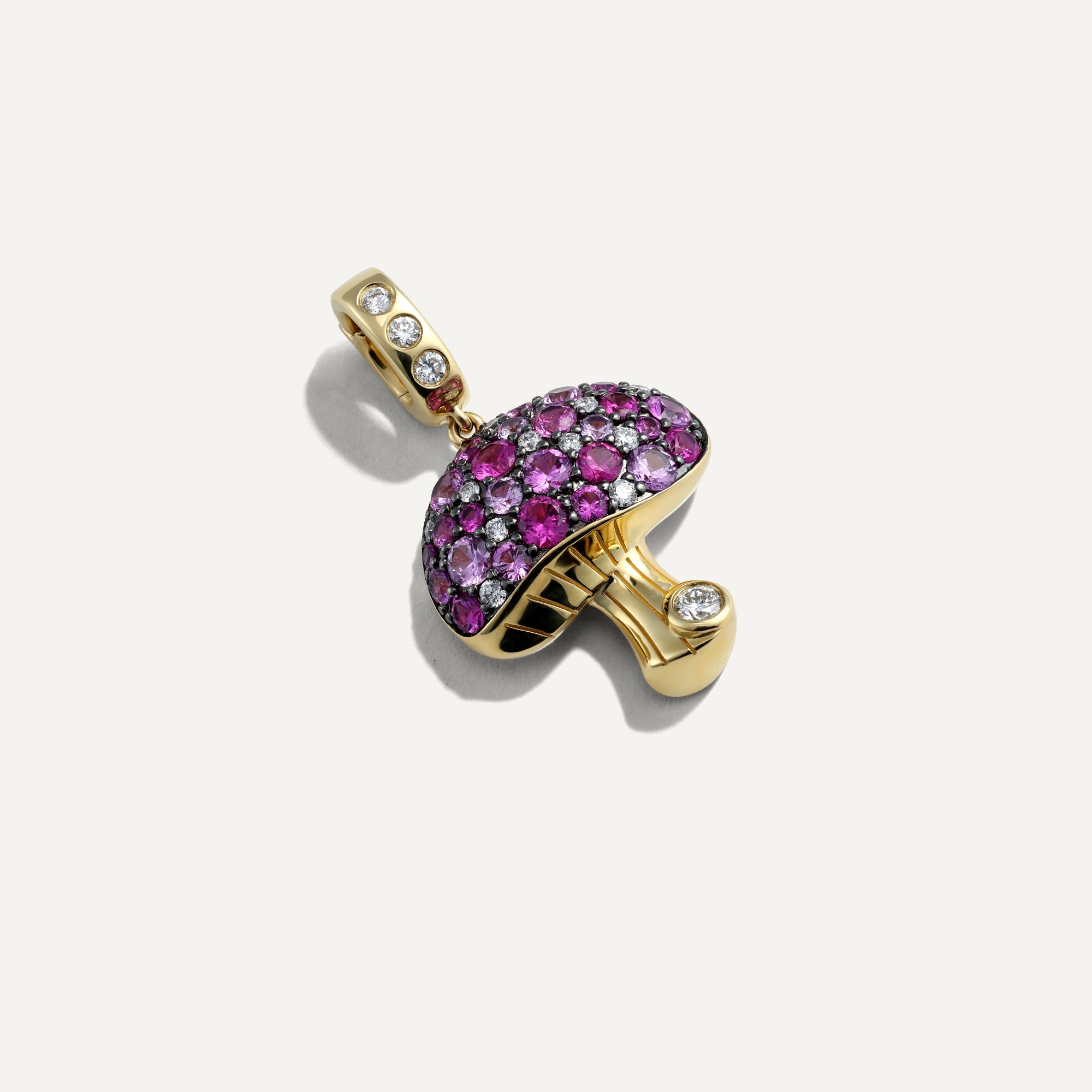 Gold pendant with pink gemstones on a white background