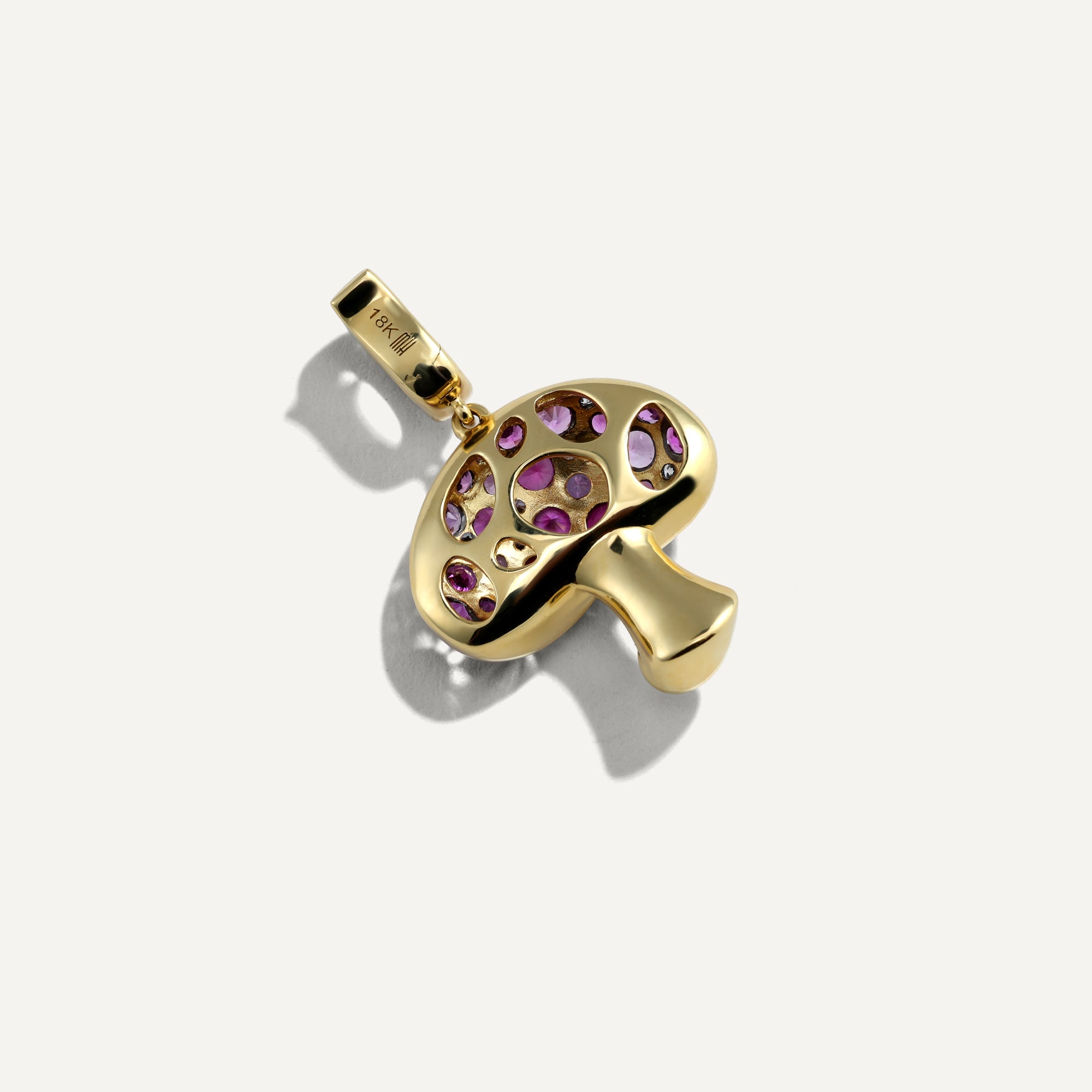 Gold pendant with purple gemstones on a white background