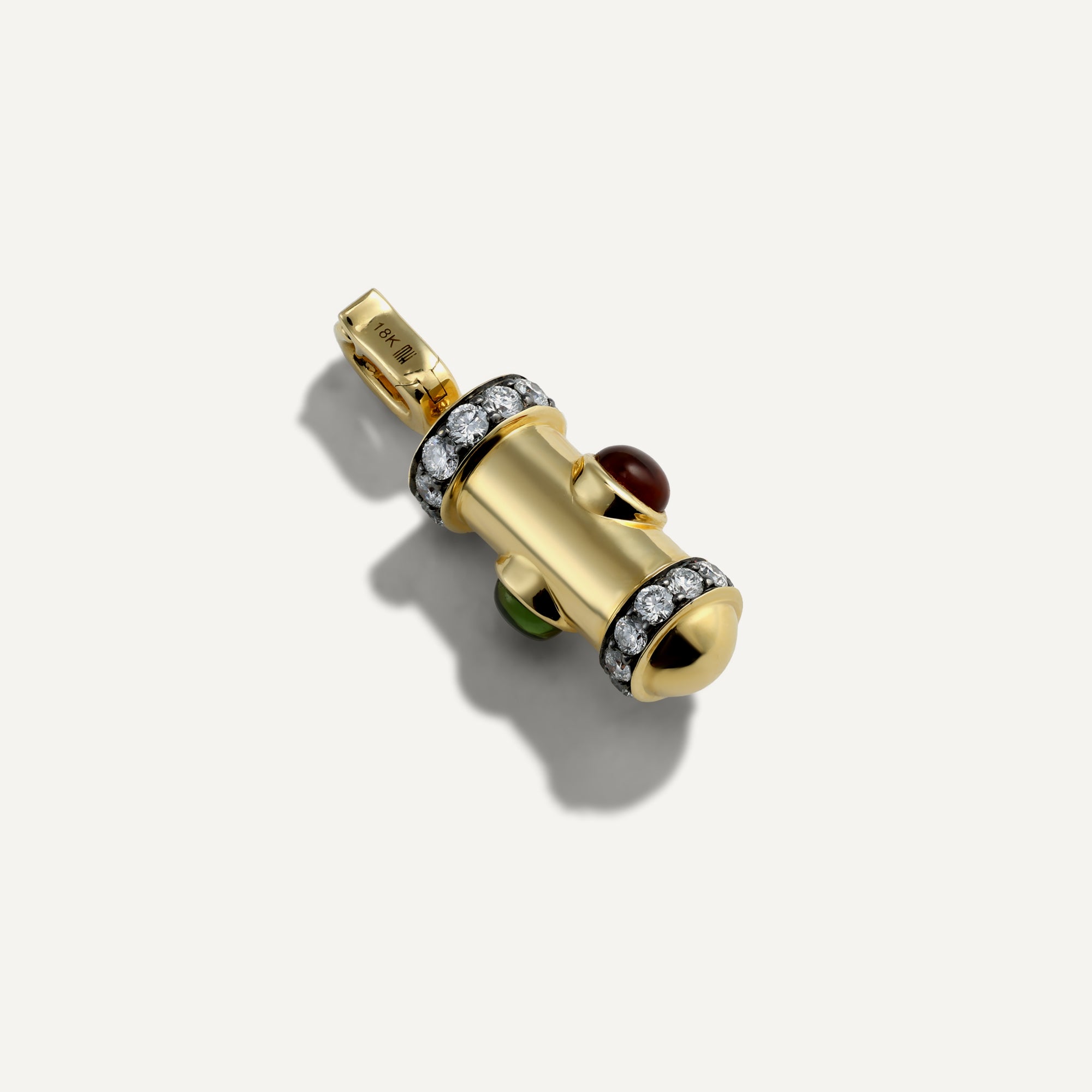 Gold pendant with gemstones on a light gray background