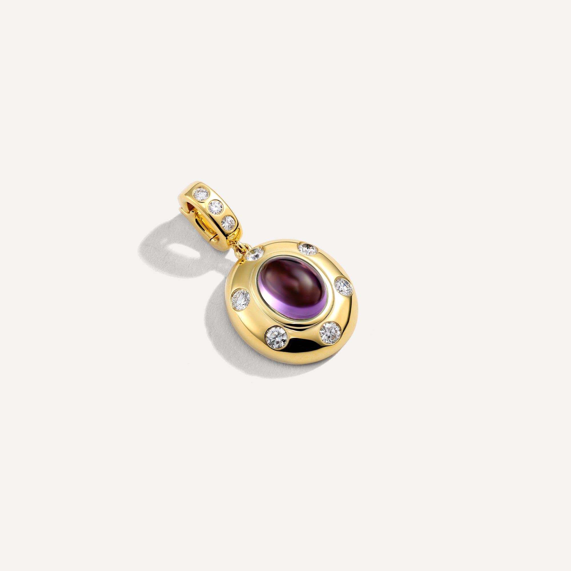 Gold pendant with a purple gemstone on a white background
