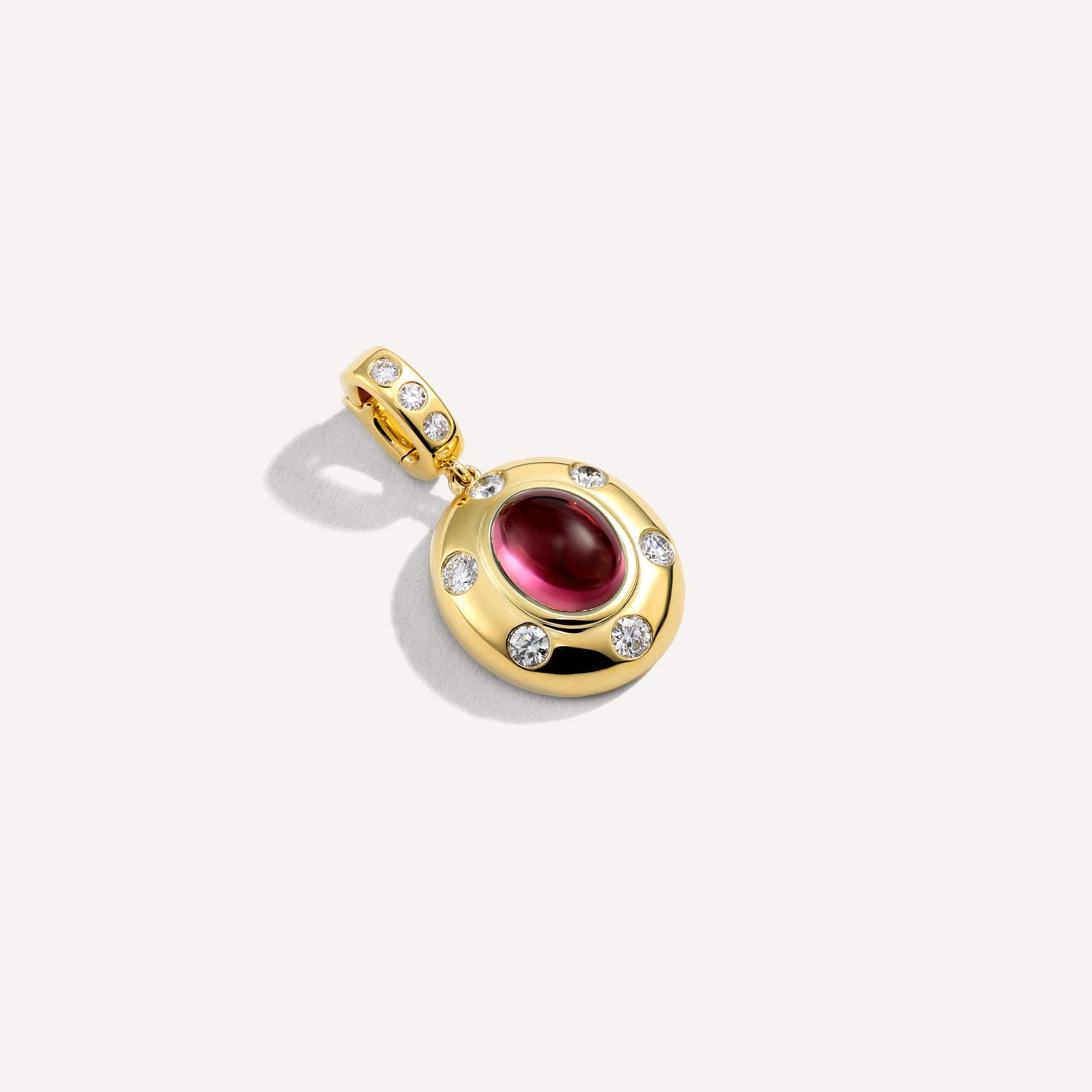 Gold pendant with a red gemstone on a white background